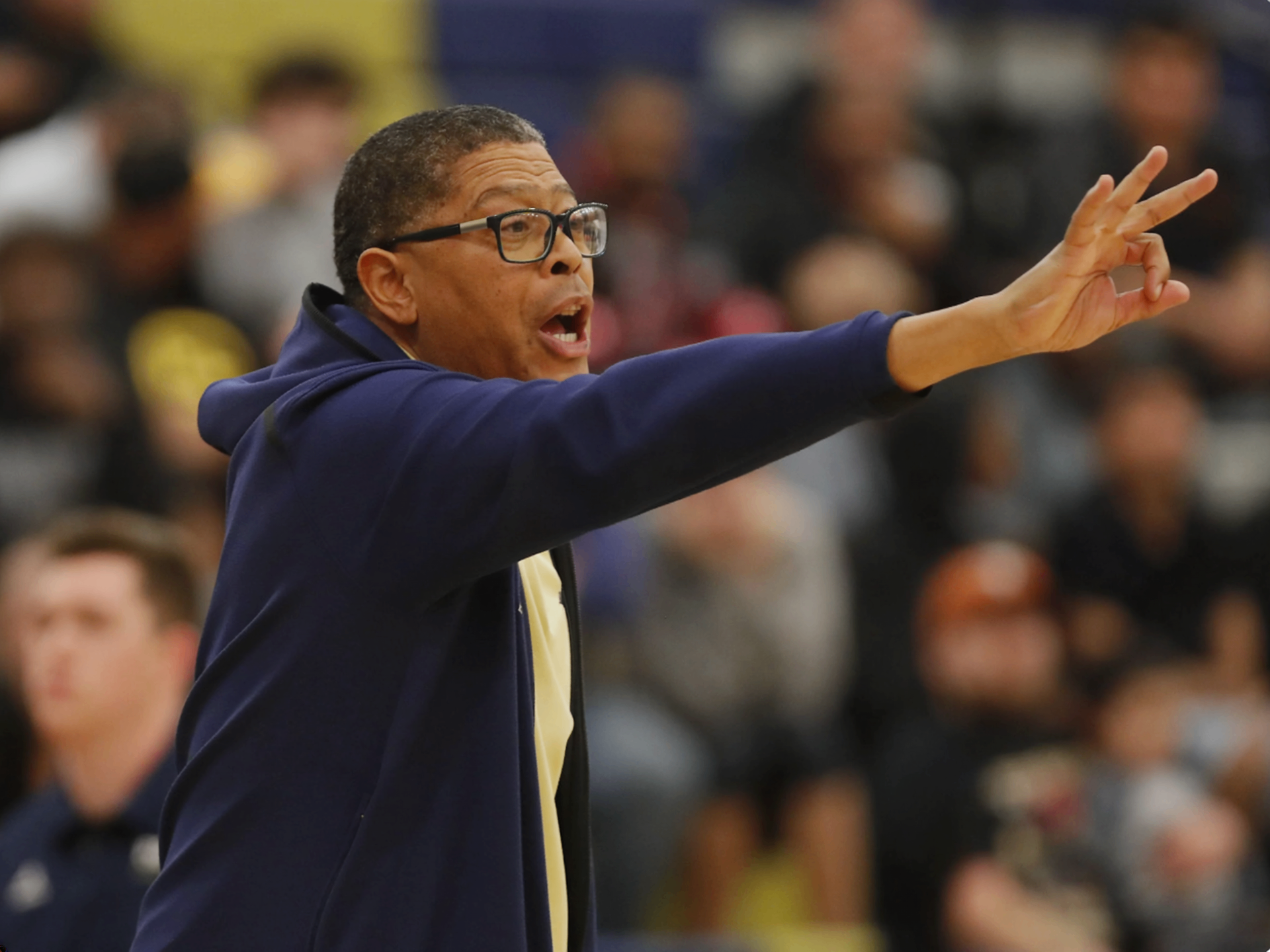 Coach Gino Crump directing his team with a pointed gesture during a game